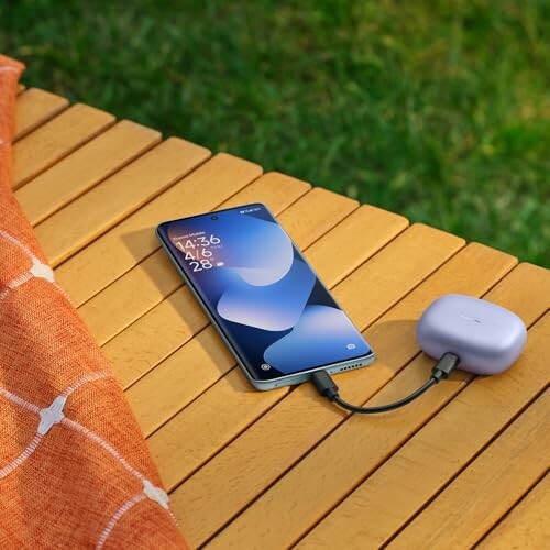 Teléfono inteligente cargando en una mesa al aire libre.